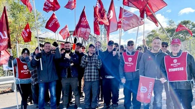 一群受雇于圣劳伦斯海道管理公司的工会成员在警戒线上举着旗帜.